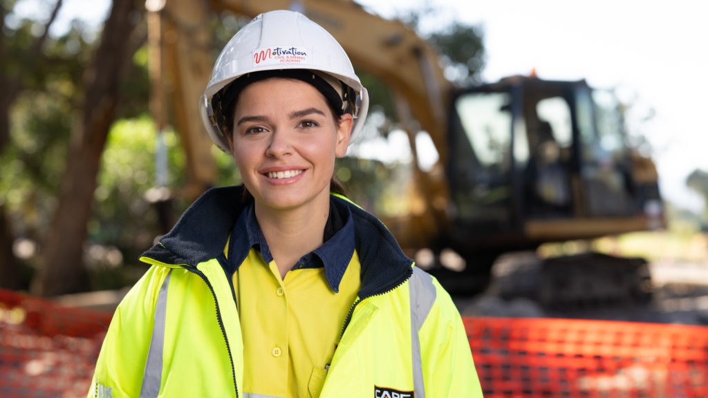 Construction worker with hard hat standing in front of excavator 