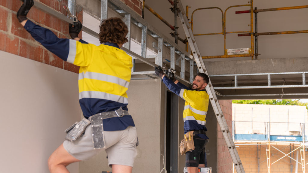 Two construction workers carrying a ladder