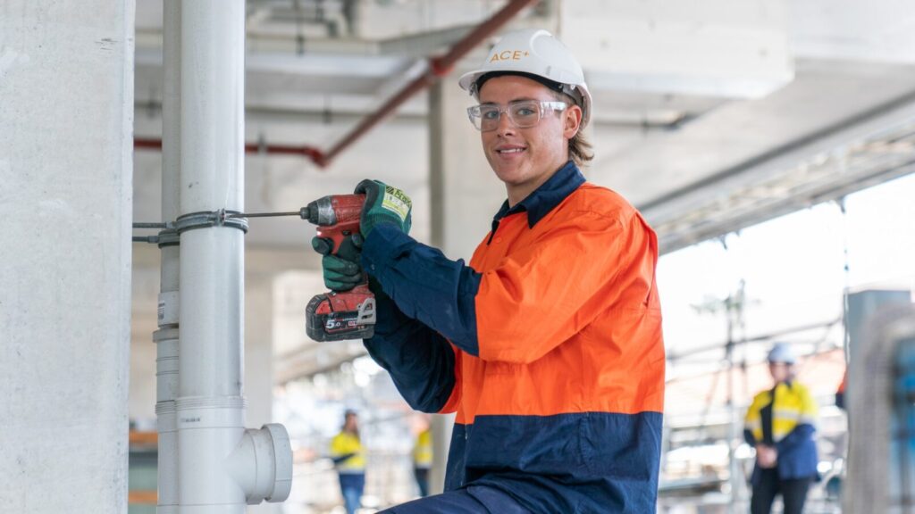 Construction workers wearing a hardhat and drilling while smiling