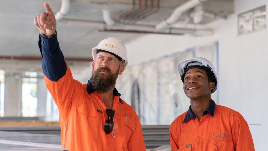 One construction workers pointing something out to another construction worker