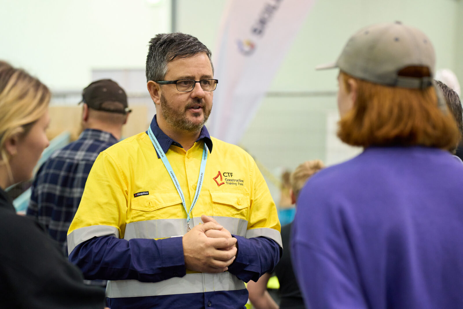 Man in high vis speaking to some people